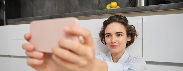 Close-up-Porträt einer offenen jungen Frau, die mit einem Smartphone eine Selfie macht, indem sie eine Handy-Foto-App verwendet.