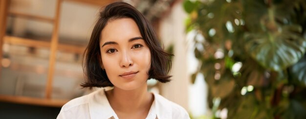 Close-up-Porträt einer schönen romantischen jungen asiatischen Frau, die lächelt und glücklich aussieht, die gemütlich sitzt