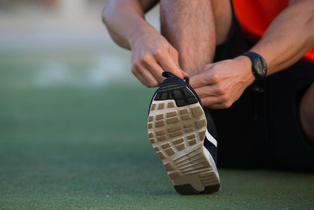 Close-up von männlichen Händen binden Sportschuhe