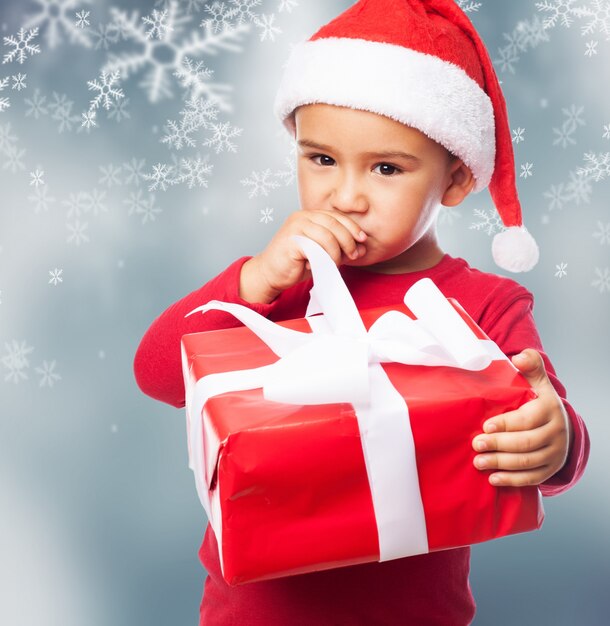 Close-up von nachdenklichen kleinen Jungen mit einem Geschenk