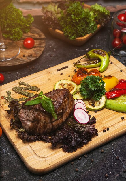 Club Beef Steak mit Pfeffersauce und gegrilltem Gemüse auf Schneidebrett