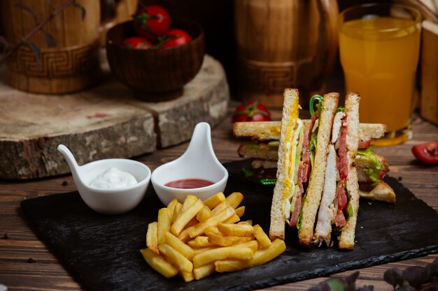 Club Sandwiches in Toast mit Pommes Frites und Saucen.