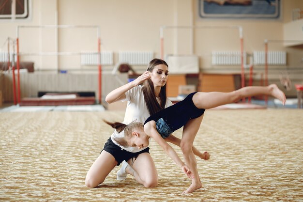 Coach mit Student. Mädchen Turnerinnen, führt verschiedene Gymnastikübungen und Springen. Kinder und Sport, ein gesunder Lebensstil.