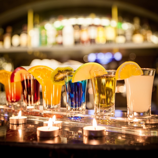 Cocktail-Aufnahmen von der Seite mit Zitronen- und Apfelscheibe und Kerzen an der Bar