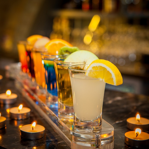 Cocktail-Aufnahmen von der Seite mit Zitronenscheibe, Kiwischeibe und Kerzen