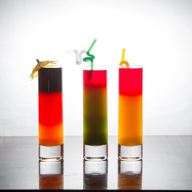 Cocktailaufnahmen der Seitenansicht mit Cocktailschirm und Saftstroh im Tisch