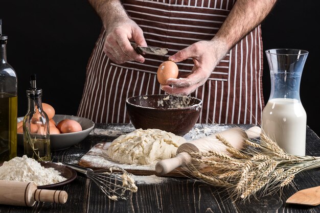 Cook bricht das Ei genau, um Teig zu machen. Zutaten zum Kochen von Mehlprodukten oder Teig Brot, Muffins, Kuchen, Pizzateig. Platz kopieren