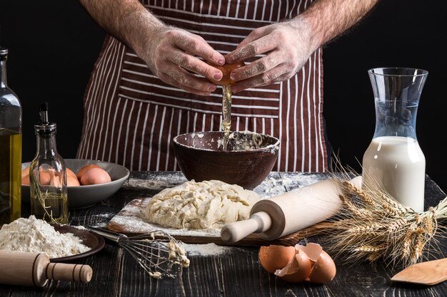 Cook bricht das Ei genau, um Teig zu machen. Zutaten zum Kochen von Mehlprodukten oder Teig Brot, Muffins, Kuchen, Pizzateig. Platz kopieren