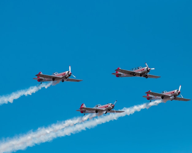 Kostenloses Foto coole flugzeugshow mit fliegenden flugzeugen und weißem rauch am blauen himmel