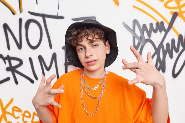 Coole Teenager in modischen Kleidern macht Ihre Geste Rap oder Hip-Hop-Musik hat stilvolle Look-Posen gegen bunte Graffiti-Wand verbringt Freizeit mit Freunden