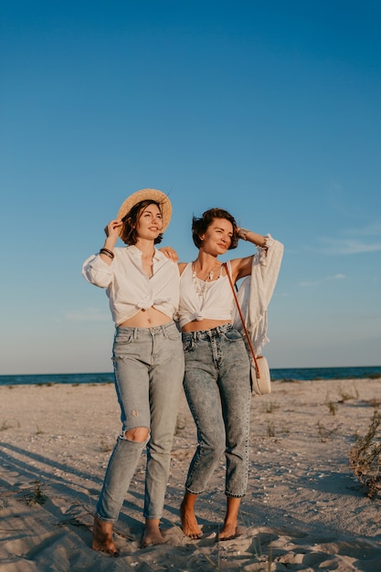 Coole zwei junge Frauen, die Spaß am Sonnenuntergangsstrand haben, schwule lesbische Liebesromantik