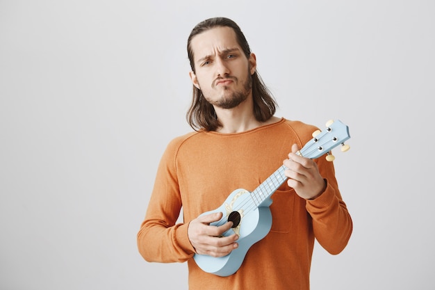 Cooler hübscher Kerl, der Ukulele spielt