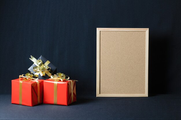 Corkboard und Weihnachtsgeschenkboxen mit Kopienraum lokalisiert auf einem dunklen Hintergrund