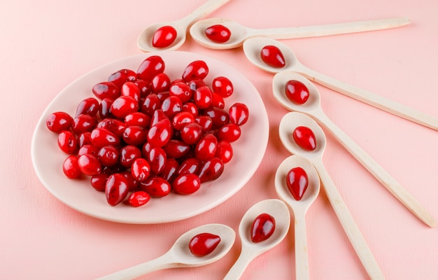 Cornel Beeren in Holzlöffeln und Teller auf rosa. High Angle View.