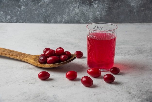 Kostenloses Foto cornels in einem holzlöffel und einem glas saft.