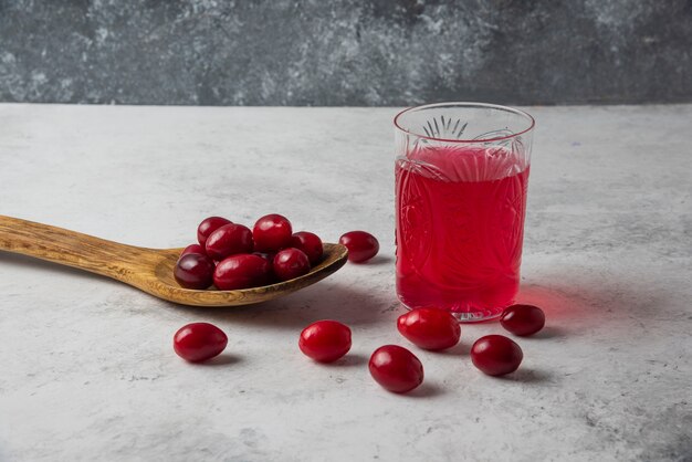 Cornels in einem Holzlöffel und einem Glas Saft.