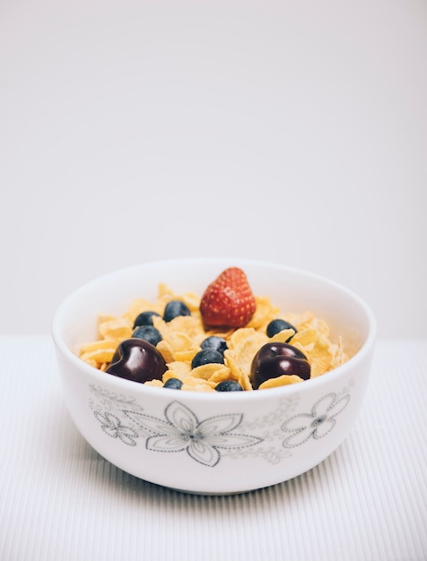 Cornflake-Getreide mit Beeren in einer Schüssel auf weißem Hintergrund