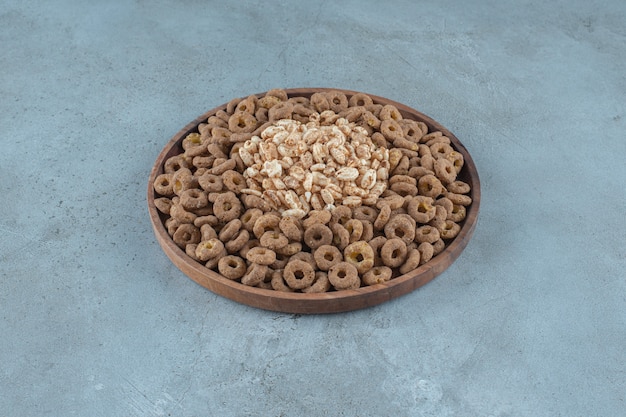 Cornflakes in der Holzplatte, auf blauem Hintergrund. Foto in hoher Qualität