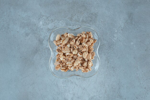 Cornflakes in einem Milchkaffeeglas, auf blauem Hintergrund.