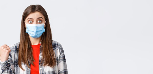 Coronavirus Ausbruch Freizeit auf Quarantäne soziale Distanzierung und Emotionen Konzept Erstaunte und beeindruckte süße Frau in medizinischer Maske, die zeigt, wie sie auf der linken Seite über Banner spricht