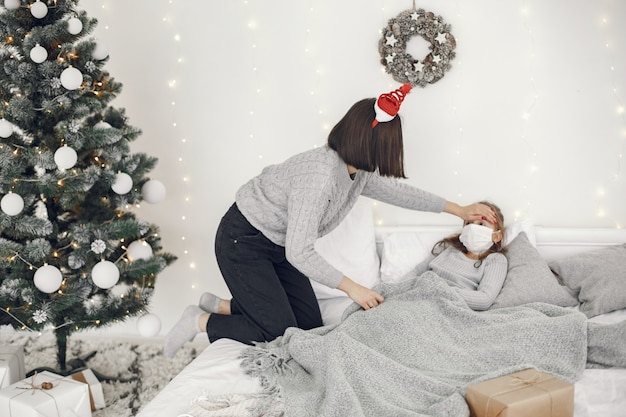 Coronavirus bei einem Kind. Mutter mit Tochter. Kind liegt in einem Bett. Frau in einer medizinischen Maske.