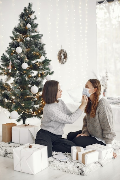 Coronavirus und Weihnachtskonzept. Frau hilft ihrer Freundin, eine Maske zu tragen.