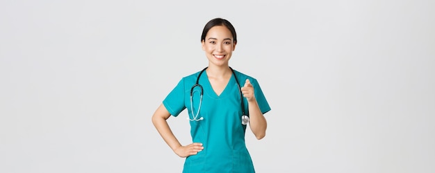 Covid Gesundheitspersonal Pandemiekonzept zuversichtlich lächelnde asiatische professionelle Arztkrankenschwester in Scrub...