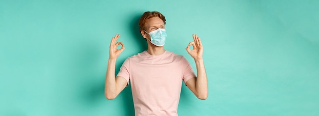 Covid-Pandemie und Lifestyle-Konzept Fröhlicher rothaariger Mann in medizinischer Maske, der in ca