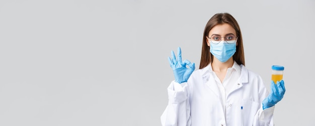 Covid19 medizinische Forschung Gesundheitspersonal und Quarantänekonzept Professioneller Arzt in Peelings medizinische Maske und Handschuhe, die die Urinprobe des Patienten halten und ein Okay-Zeichen zeigen, das die Durchführung von Tests genehmigt