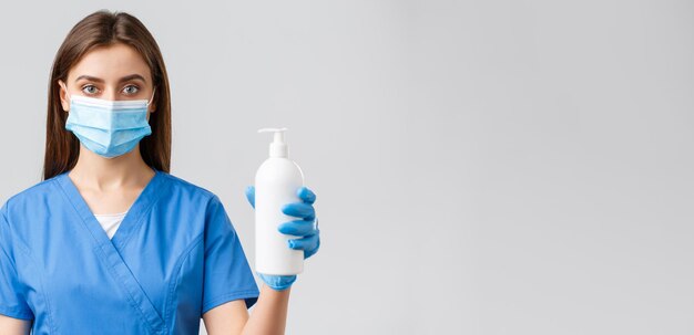 Covid19 verhindert Virus-Gesundheitspersonal und Quarantänekonzept Ernsthaft aussehende medizinische Krankenschwester oder Arzt in blauen Peelings und medizinischer Maske mit Händedesinfektionsmittel oder Seife