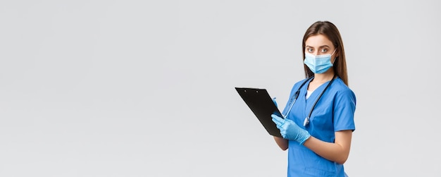 Covid19 verhindert Virus-Gesundheitspersonal und Quarantänekonzept Professionelle Krankenschwester oder Ärztin in blauer medizinischer Maske und Handschuhen, die Patienteninformationen mithilfe der Zwischenablage aufschreiben