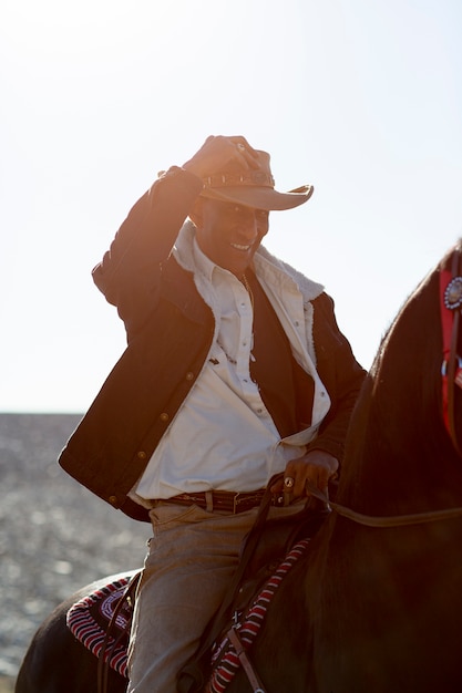 Kostenloses Foto cowboy-silhouette mit pferd gegen warmes licht