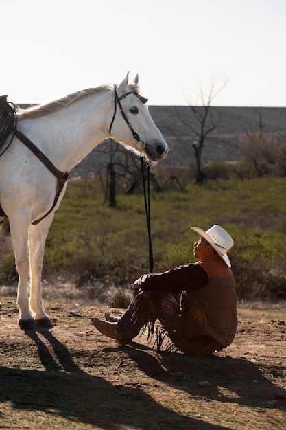 Kostenloses Foto cowboy-silhouette mit pferd gegen warmes licht