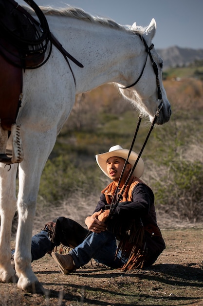 Kostenloses Foto cowboy-silhouette mit pferd gegen warmes licht