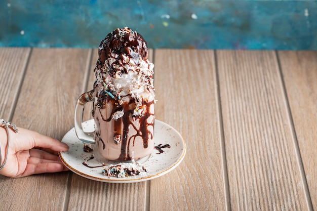 Cremiger Vanille-Milchshake mit Schokoladensauce in einer weißen Untertasse