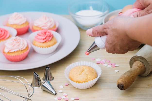 Kostenloses Foto cremiger vanille-zuckerguss wird auf cup-kuchen mit individueller größe gewirbelt