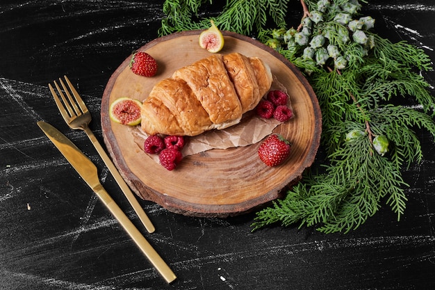 Croissant mit Beeren auf Holzplatte.