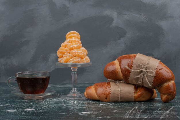 Croissant mit heißem Tee und Glasplatte Mandarine