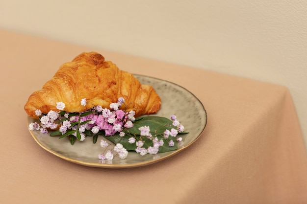 Croissant mit hohem Winkel und Blumen auf dem Teller