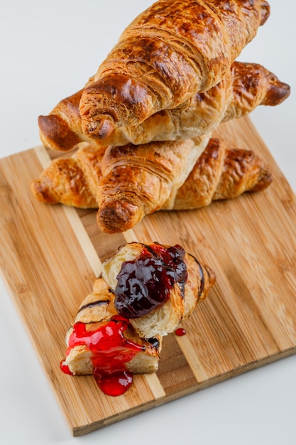 Croissant mit Marmelade auf Weiß und Schneidebrett, hohe Winkelansicht.