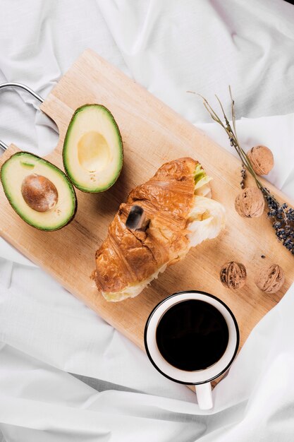 Croissant mit Messer zwischen Avocado und Kaffee