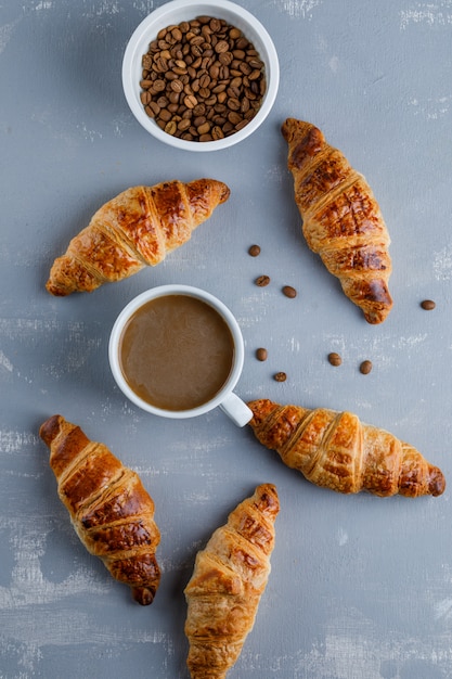 Croissant mit Tasse Kaffee, Kaffeebohnen, Draufsicht.