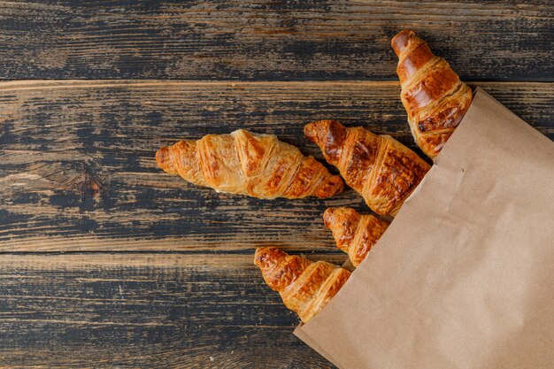 Croissants in einer Papiertüte auf einem Holztisch. flach liegen.