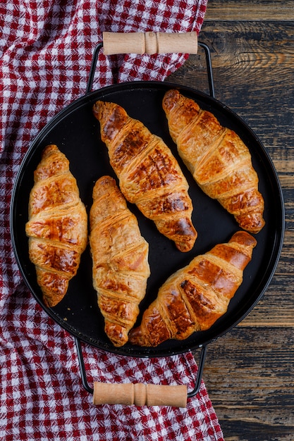 Croissants in einer Pfanne auf Holz- und Küchentuch. flach liegen.