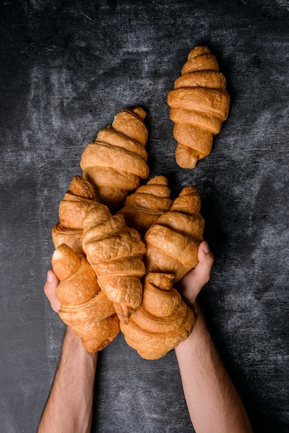 Croissants in Händen auf grauem Tisch.