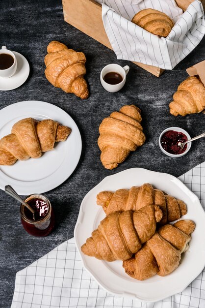 Croissants, Kanne mit Marmelade und Kaffeetasse beiseite auf grauem Tisch