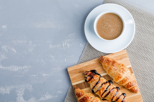 Croissants mit Kaffee, Schneidebrett, flach liegen.