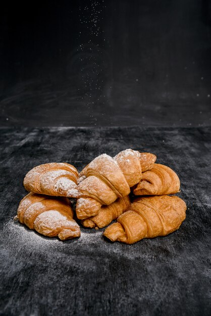 Croissants mit Puderzucker auf grauem Tisch.