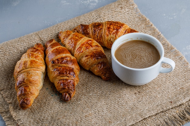 Croissants mit Tasse Kaffee auf Gips und Sack