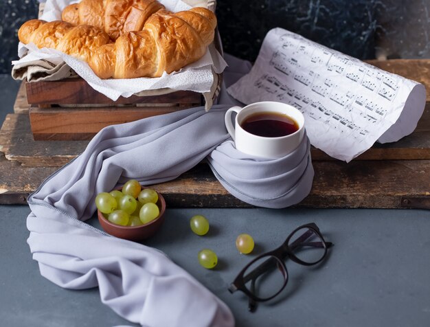 Croissants, Trauben und eine weiße Tasse Tee